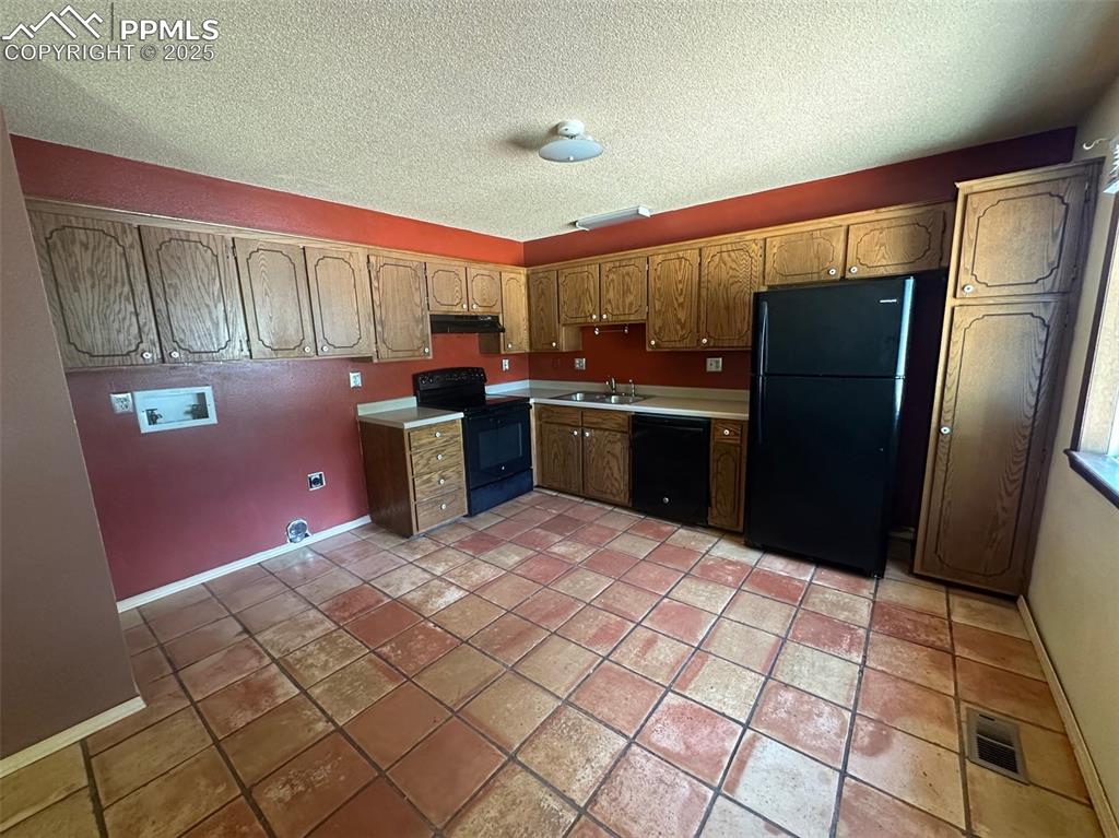Image 5 of 22: Kitchen featuring black appliances, under cabinet range hood, a textured ce