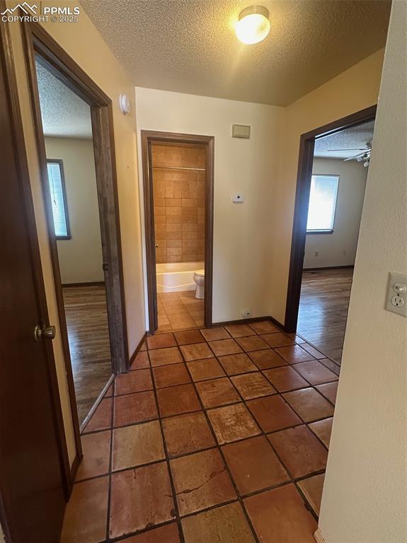 Image 6 of 22: Hallway featuring a textured ceiling and Mexican tile patterned flooring