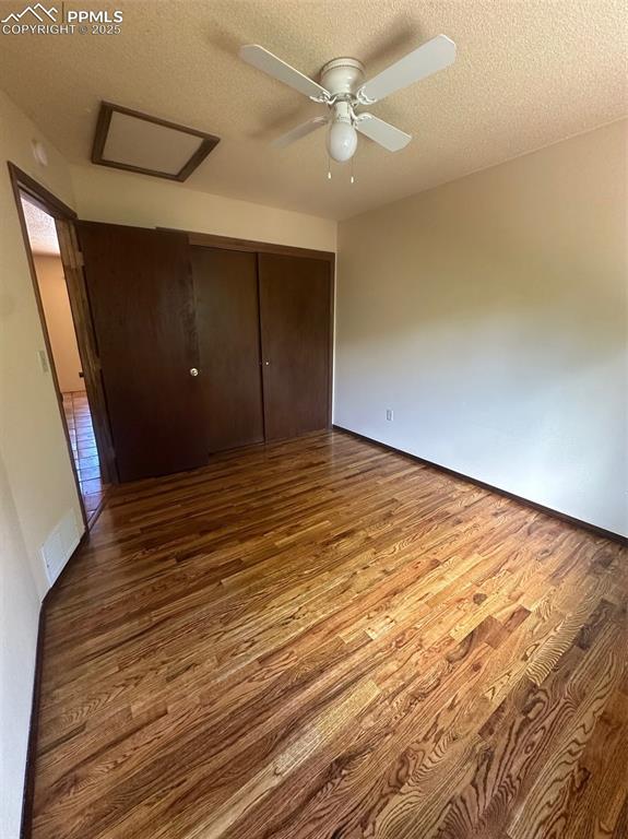 Image 7 of 22: Bedroom with attic access, wood finished floors, a closet, a textured ceili