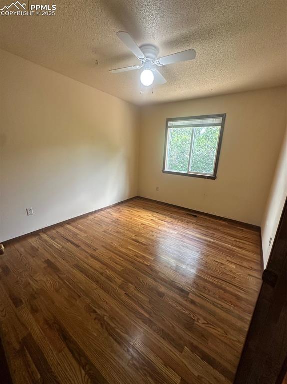 Image 8 of 22: Bedroom with a textured ceiling, wood finished floors, and a ceiling fan