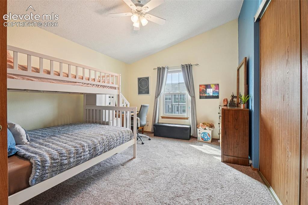 Image 11 of 24: Carpeted room featuring a vaulted ceiling with a ceiling fan, a window with