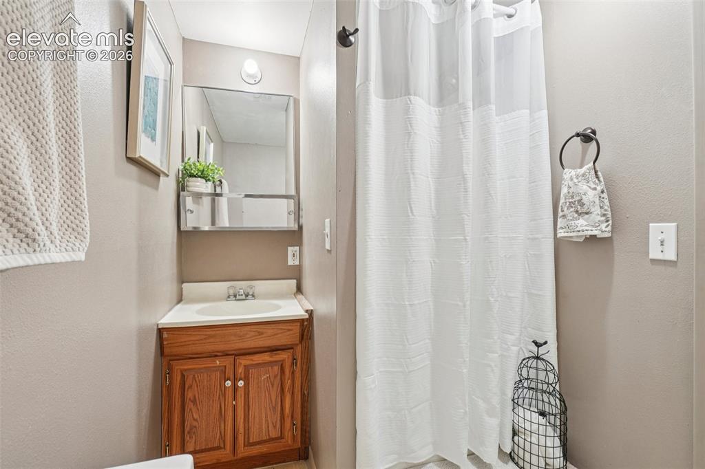 Image 18 of 24: Bathroom featuring a wood-finish vanity with an integrated sink, a mirrored