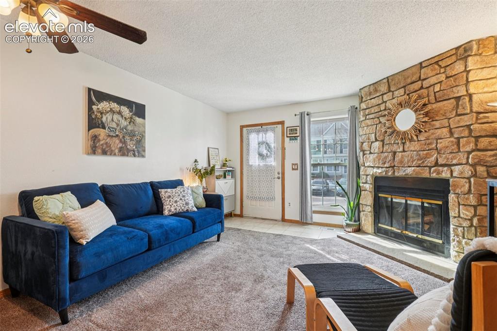 Image 5 of 24: Living area featuring a stone accent wall with a built-in fireplace, a ceil