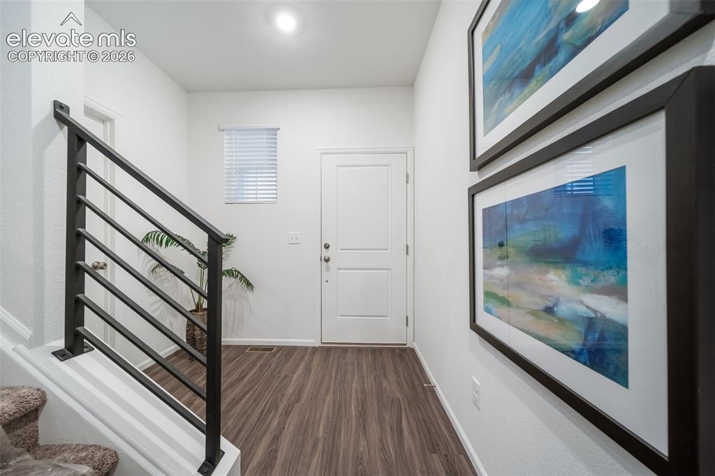 Image 11 of 41: Wood-finish flooring, white paneled door, horizontal slat window blinds, an