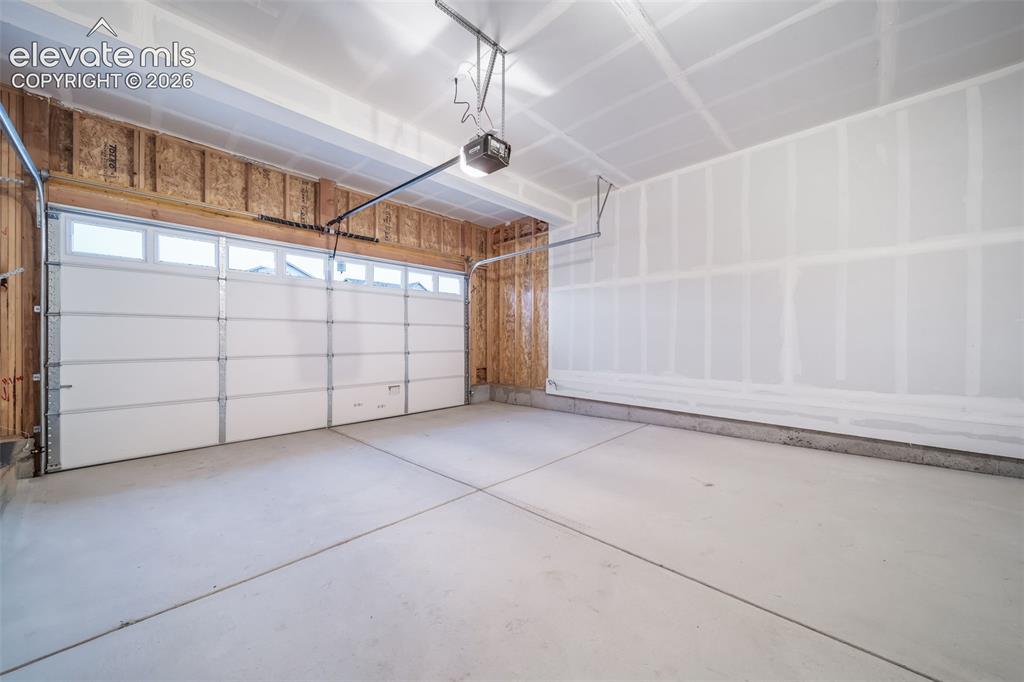 Image 15 of 41: Two-car garage with a white sectional door, upper transom windows, a concre