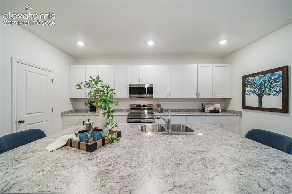Image 22 of 41: Kitchen featuring an expansive island with an integrated sink, white cabine