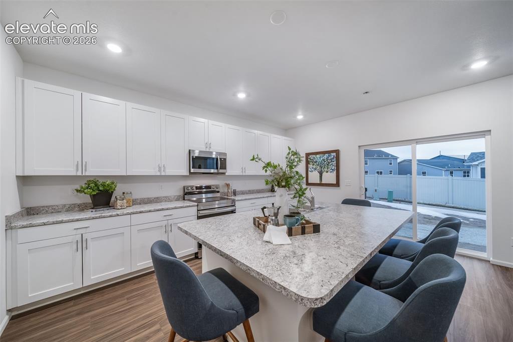Image 23 of 41: Kitchen featuring white cabinetry, stainless steel appliances, speckled sto