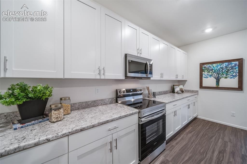 Image 24 of 41: White shaker cabinetry with brushed nickel hardware, light-toned stone-fini