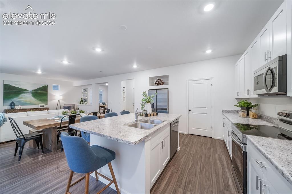 Image 25 of 41: Open-concept kitchen with white cabinetry, stainless steel appliances, and 