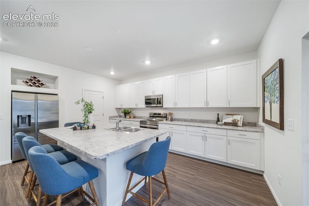 Image 26 of 41: Modern kitchen featuring a large island with an integrated sink, white cabi