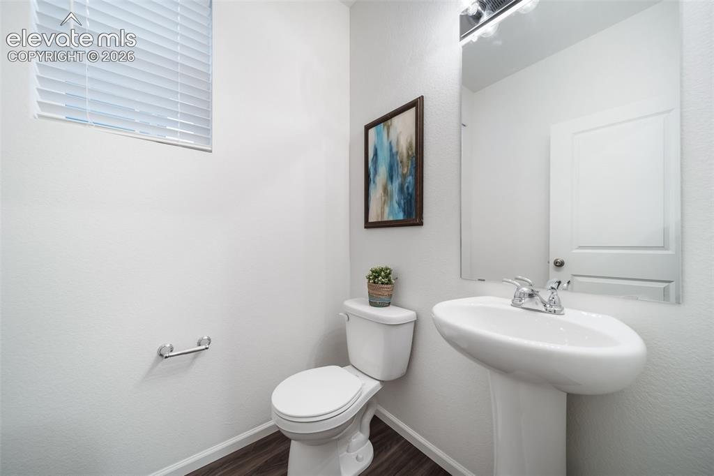 Image 31 of 41: Pedestal sink with chrome faucet, wall-mounted mirror, white toilet, and wo