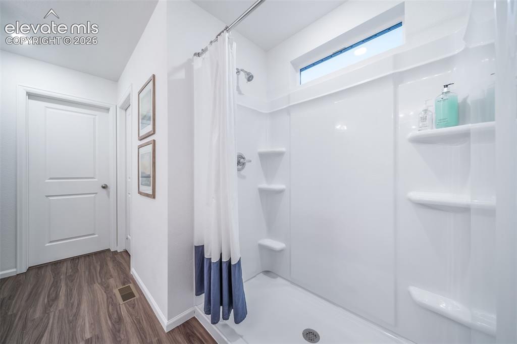 Image 32 of 41: Shower-tub combination with integrated shelving, chrome fixtures, and a tra
