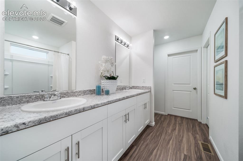 Image 34 of 41: Dual vanity with white cabinetry, light-toned countertop, and undermount si