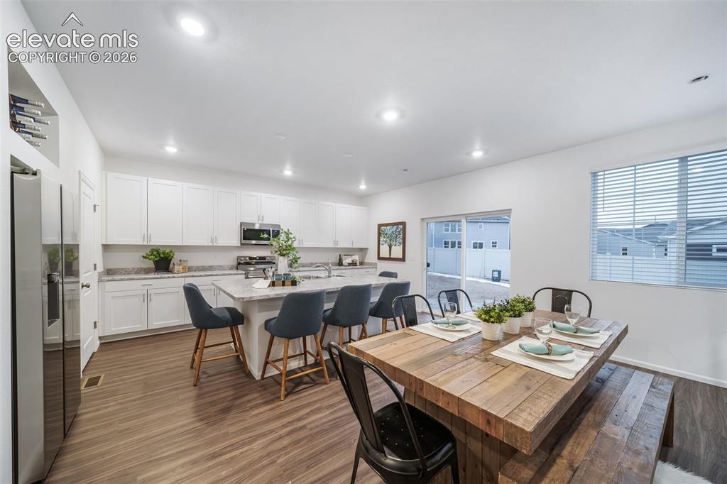 Image 9 of 41: White cabinetry with silver hardware, stainless steel appliances, wood-fini