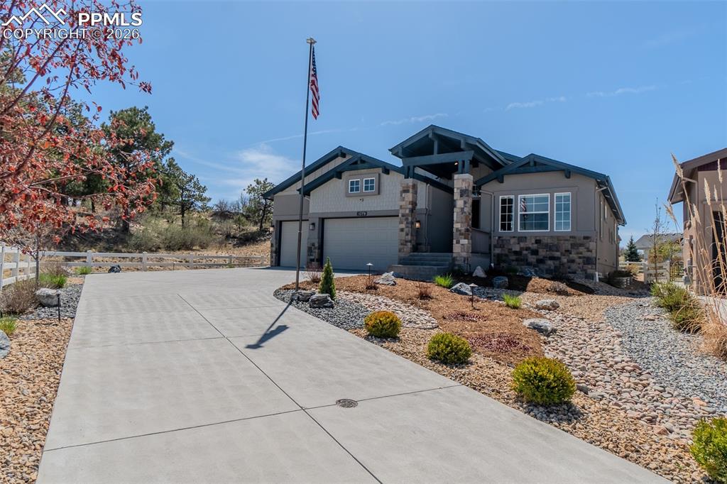 Caption: Craftsman-style exterior featuring stone accents, a covered entry, three-car garage and an impressiv