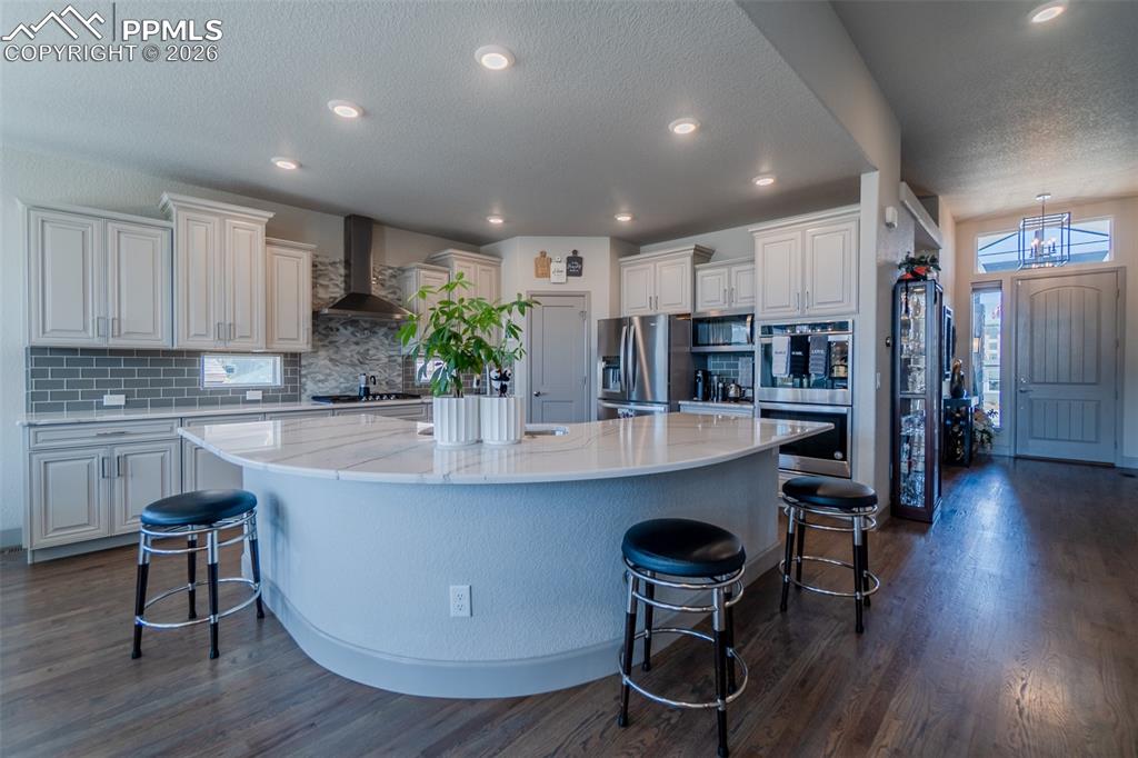 Image 10 of 49: Kitchen featuring a curved central island with a light-toned countertop, li