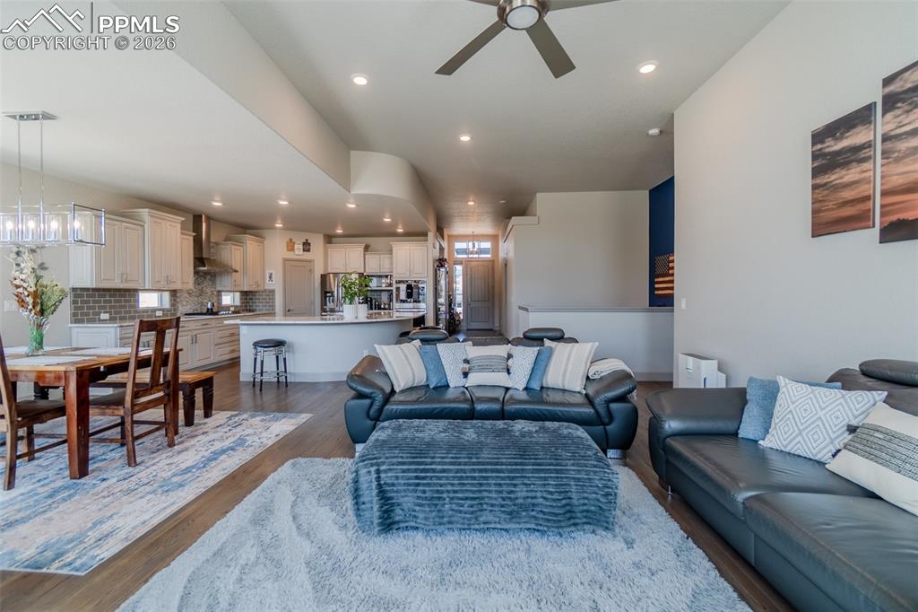 Image 12 of 49: Open-concept living area with wood-finish flooring, recessed lighting, and 