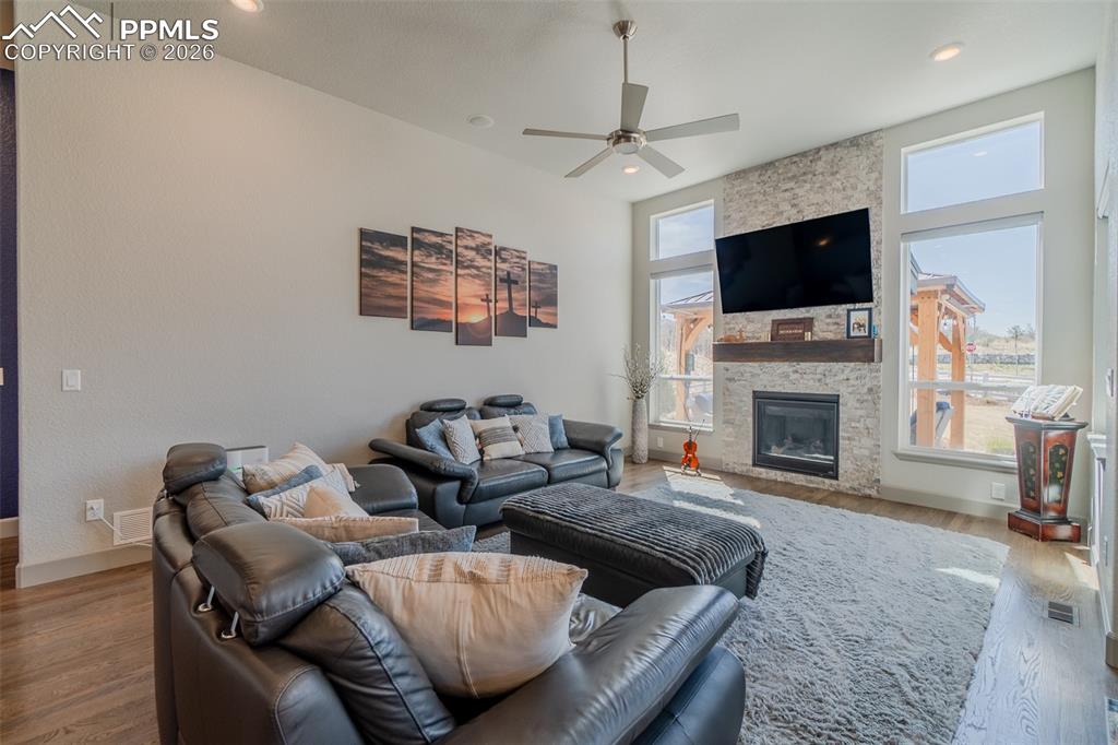 Image 15 of 49: Living room featuring a stacked stone fireplace with a wood-beam mantel, fl