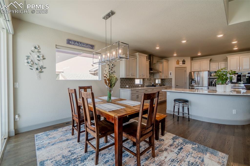 Image 16 of 49: Spacious dining area with wood-finish flooring and a rectangular chandelier