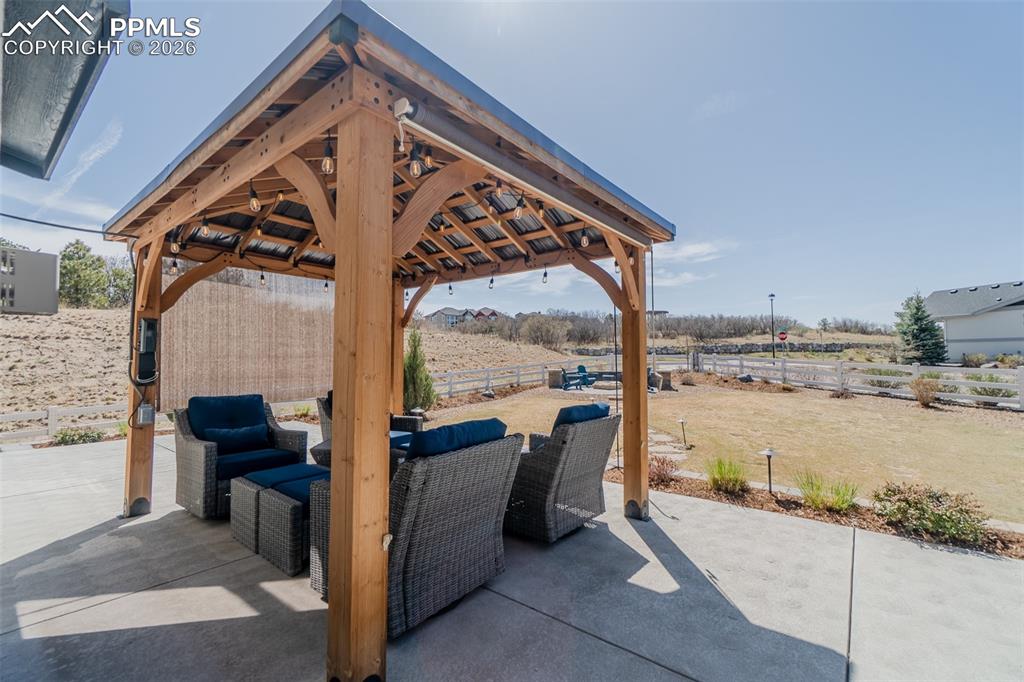 Image 23 of 49: Concrete patio with a wood-frame gazebo featuring a dark metal roof