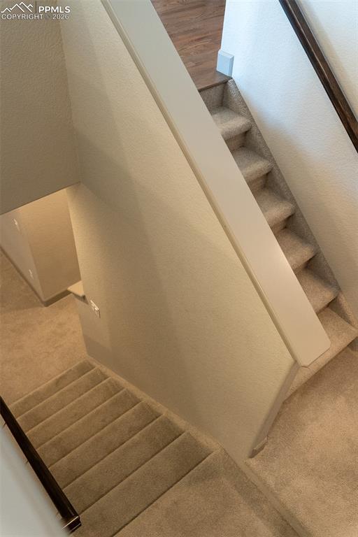 Image 34 of 49: Carpeted stairs with wood-finish handrails and white balusters