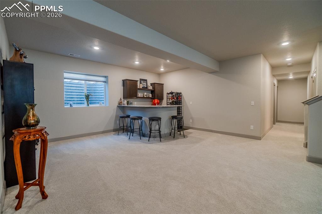 Image 39 of 49: Spacious room featuring a built-in wet bar with dark wood cabinetry and a c