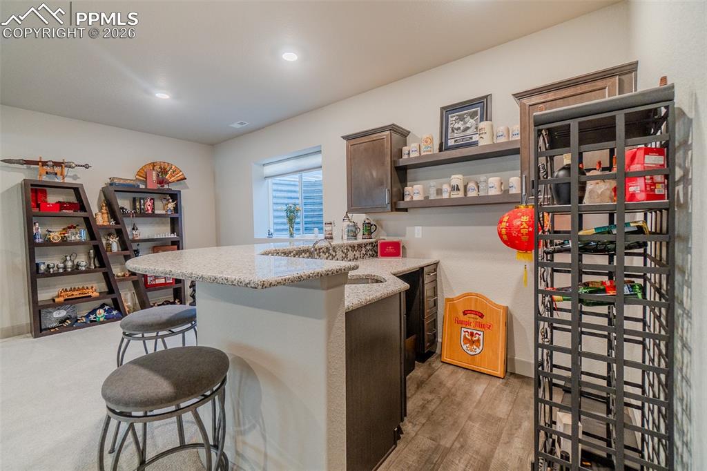 Image 40 of 49: Wet bar featuring granite countertops, undermount sink, dark wood-finish ca