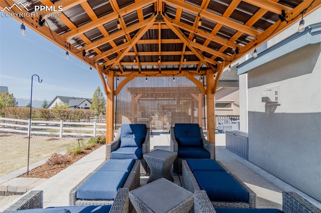 Image 43 of 49: Outdoor patio featuring a wood-frame gazebo with a metal roof and string li