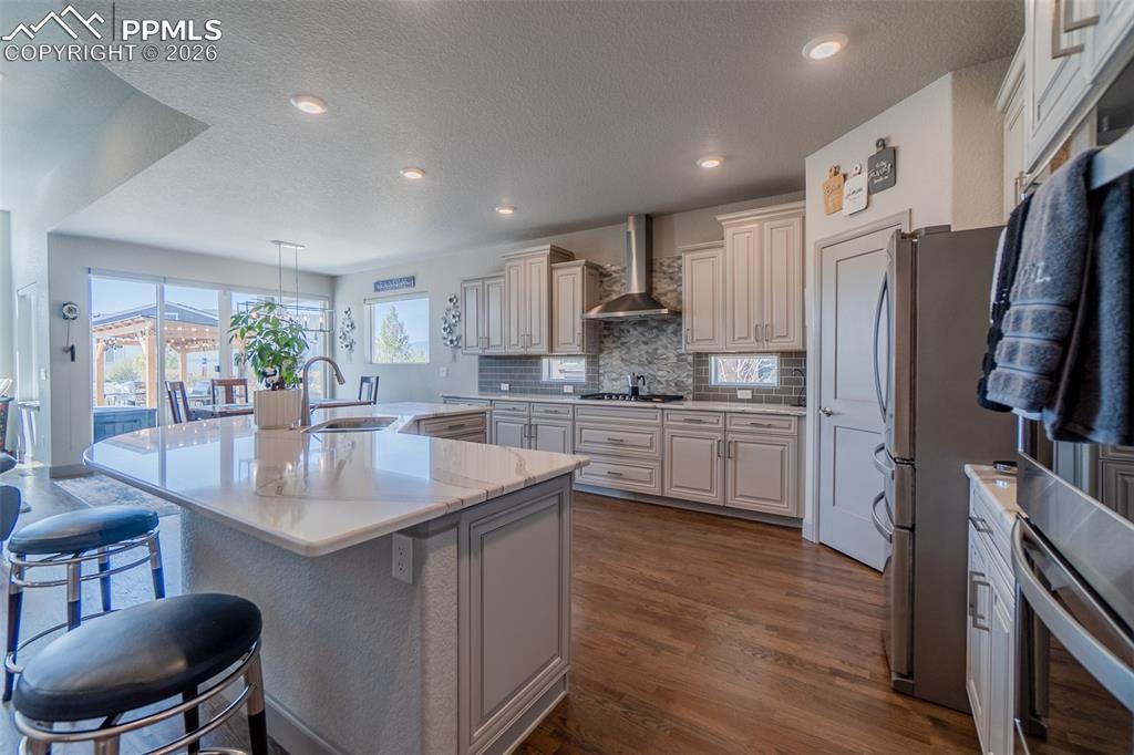 Image 5 of 49: Expansive kitchen featuring a large central island with seating, stainless 