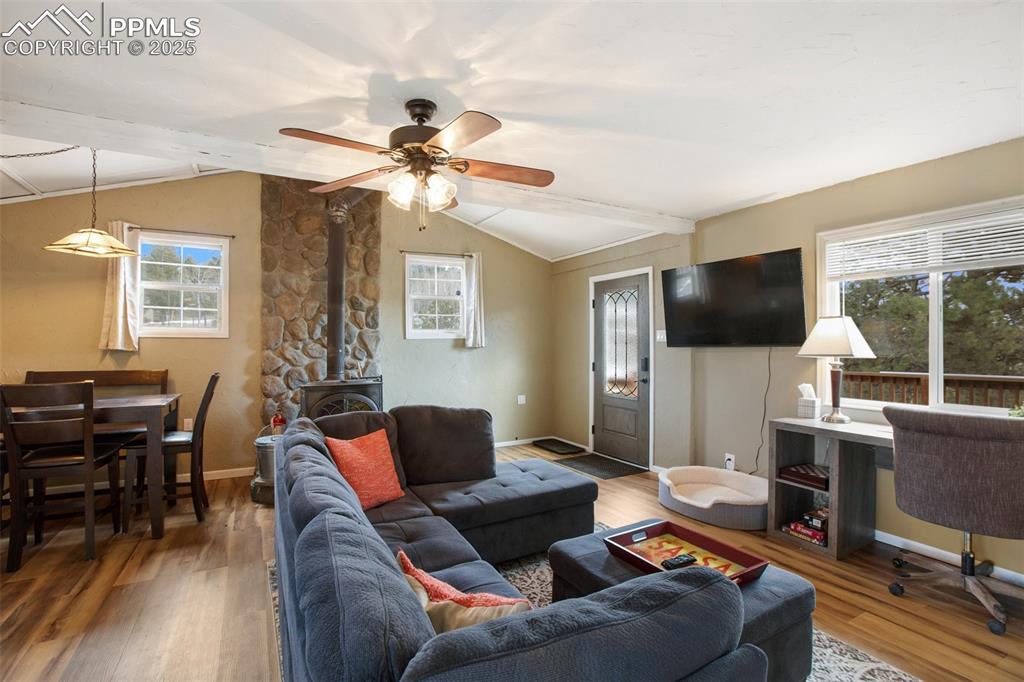 Image 13 of 36: Living room featuring a wood stove, plenty of natural light, wood finished