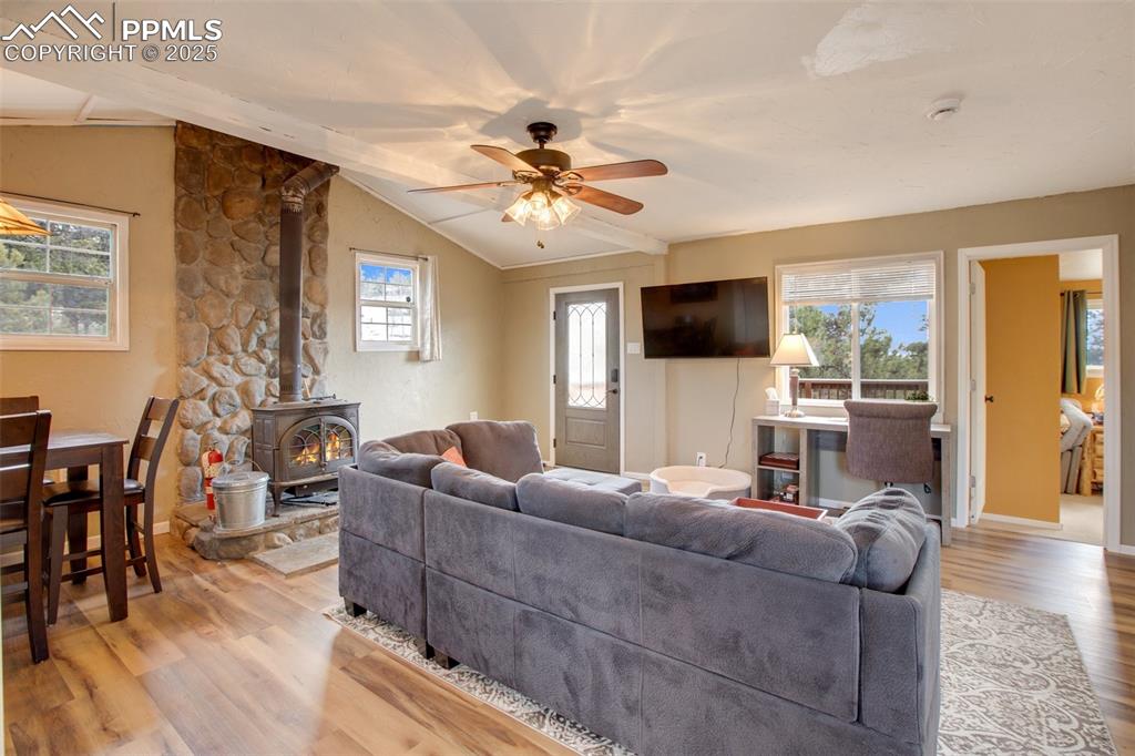 Image 14 of 36: Living area with a wood stove, healthy amount of natural light, light wood-