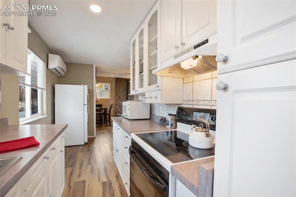 Image 20 of 36: Kitchen featuring white cabinets, white appliances, under cabinet range hoo