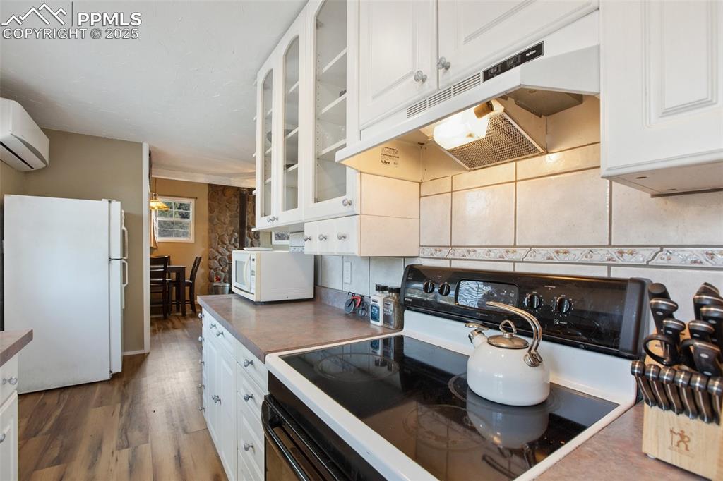 Image 21 of 36: Kitchen with white cabinets, white appliances, under cabinet range hood, wo