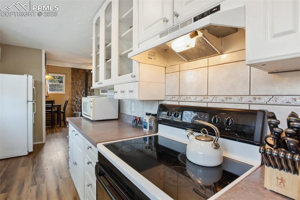 Image 22 of 36: Kitchen with white appliances, white cabinets, under cabinet range hood, wo
