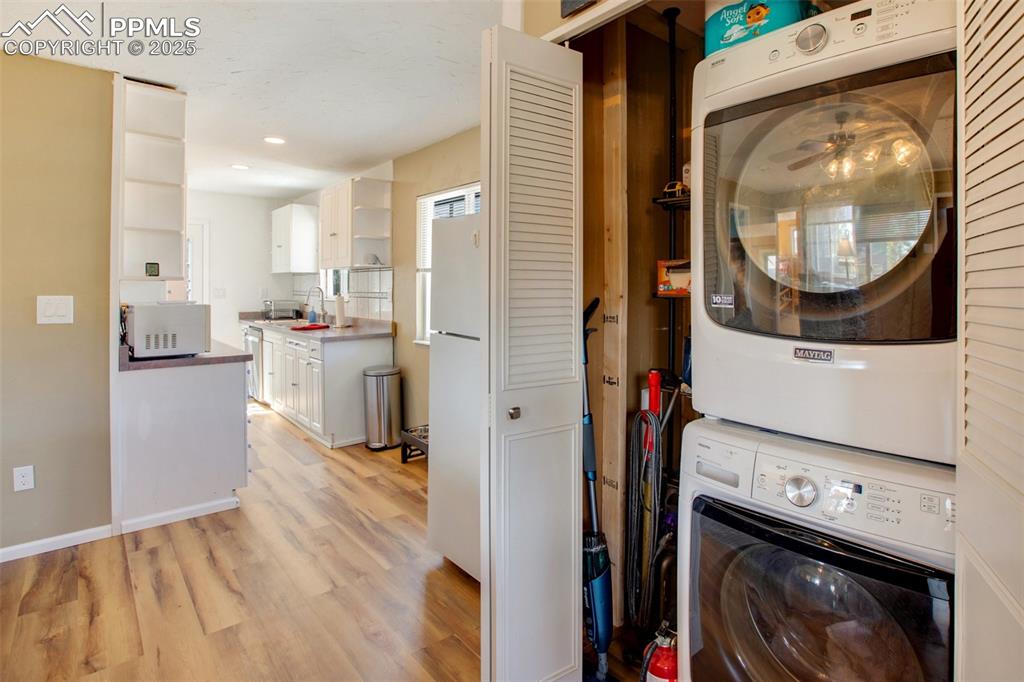 Image 29 of 36: Laundry area featuring stacked washer and clothes dryer, light wood-type fl