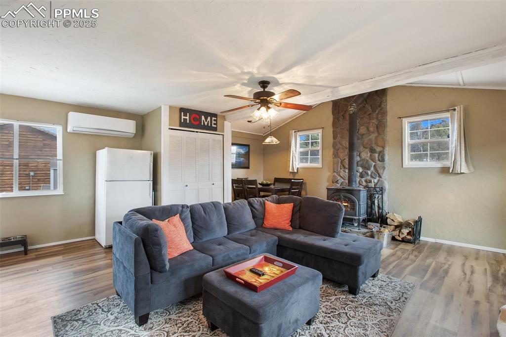 Image 3 of 36: Living area featuring a wood stove, ceiling fan, wood finished floors, loft
