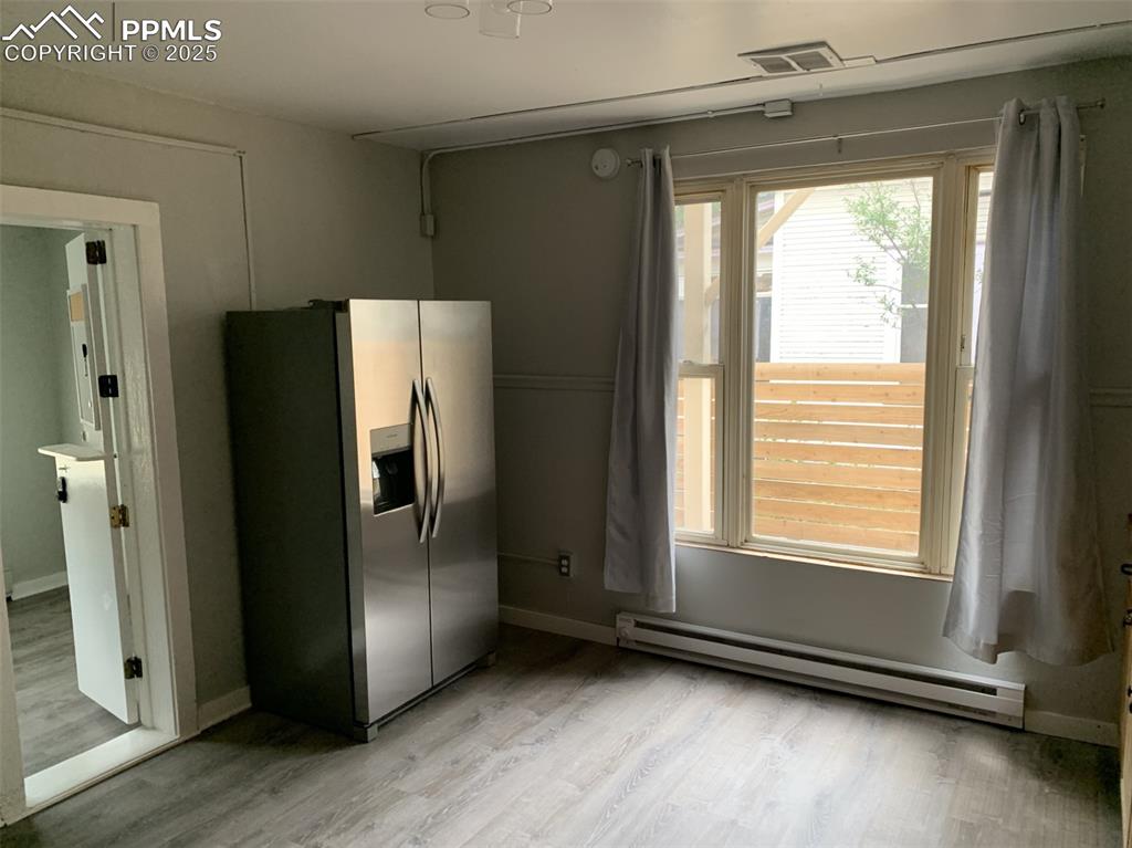 Image 10 of 49: Kitchen featuring stainless steel fridge, a baseboard heating unit, and lig