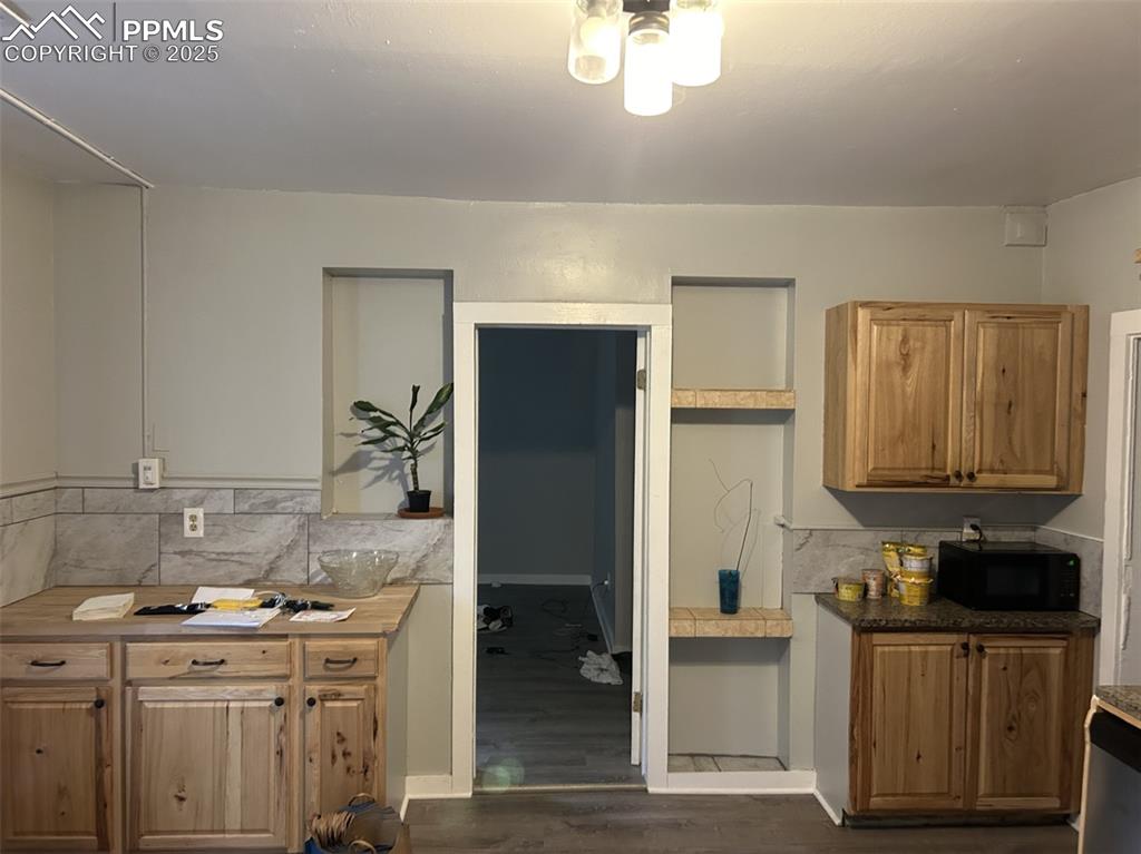 Image 11 of 49: Kitchen with dark wood-style floors, black microwave, dishwashing machine,