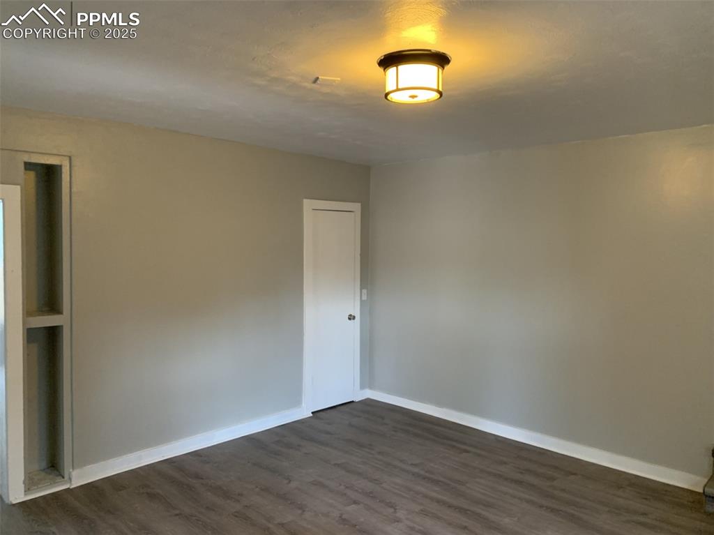 Image 14 of 49: Spare room featuring baseboards and dark wood-type flooring
