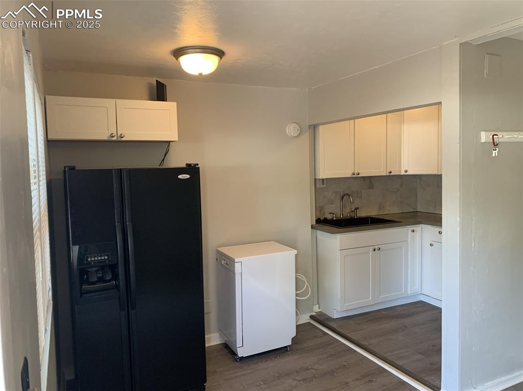 Image 17 of 49: Kitchen with black fridge with ice dispenser, fridge, dark wood finished fl