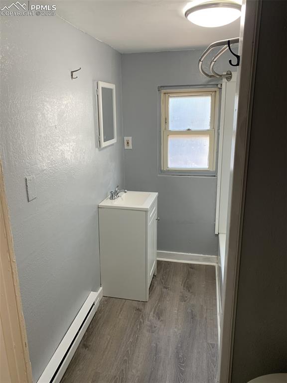 Image 21 of 49: Bathroom with vanity, baseboard heating, and wood finished floors