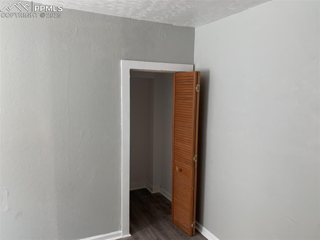 Image 22 of 49: Empty room with wood finished floors and a textured ceiling