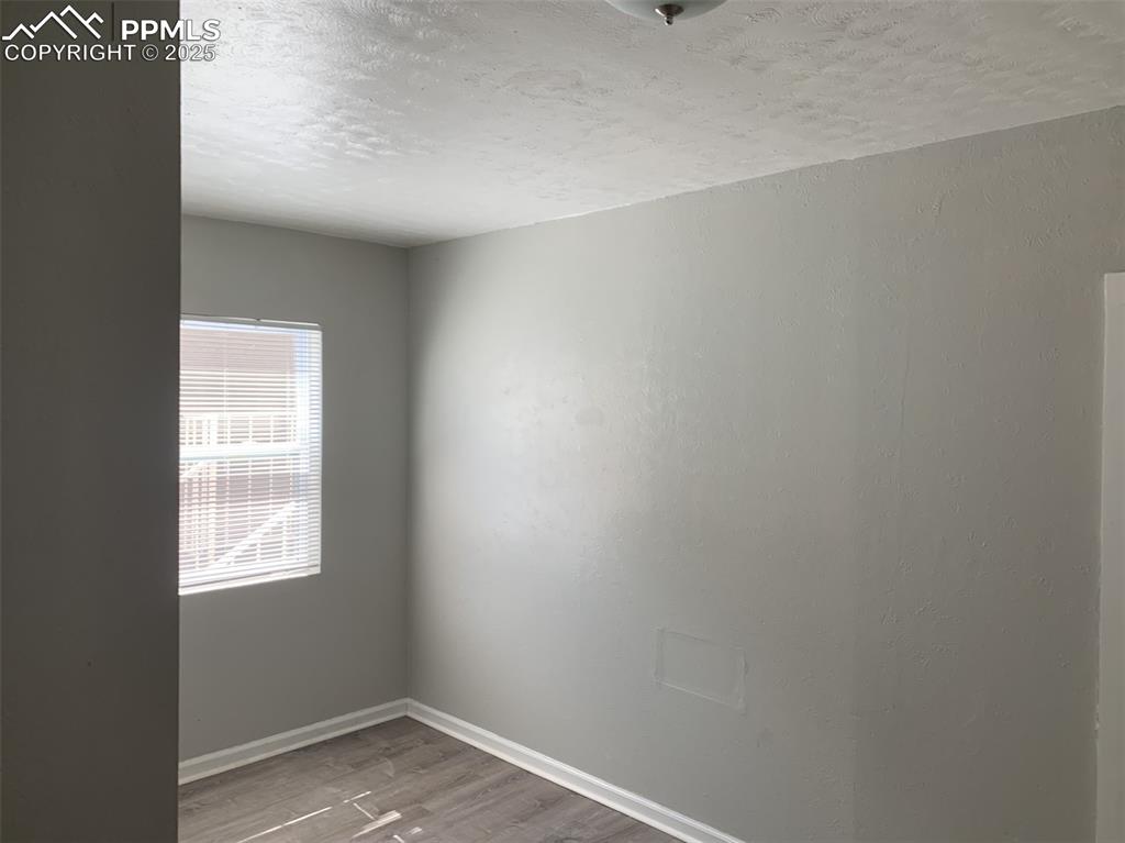 Image 23 of 49: Empty room with a textured ceiling and wood finished floors