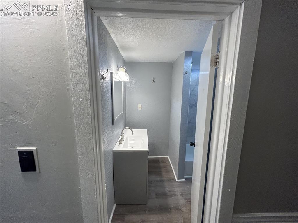 Image 27 of 49: Bathroom with a textured wall, a textured ceiling, vanity, and wood finishe