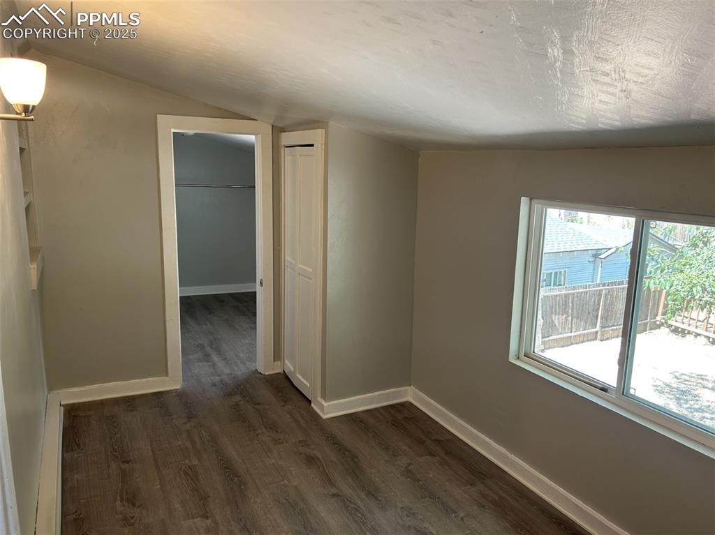 Image 36 of 49: Spare room featuring dark wood-style floors and vaulted ceiling