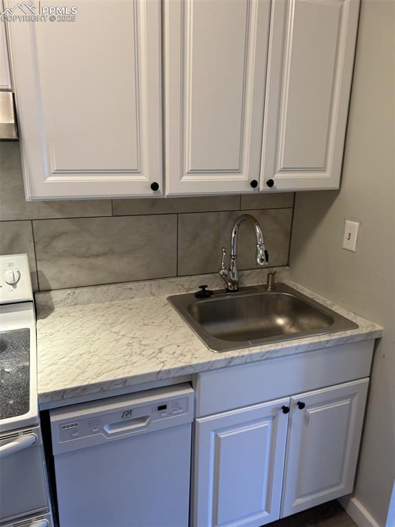 Image 38 of 49: Kitchen featuring dishwashing machine, white cabinetry, range, and decorati