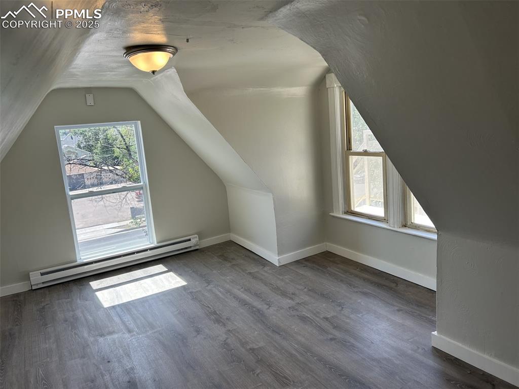 Image 44 of 49: Bonus room featuring plenty of natural light, a baseboard heating unit, dar