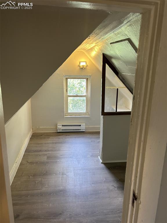 Image 49 of 49: Additional living space featuring dark wood-style flooring, vaulted ceiling