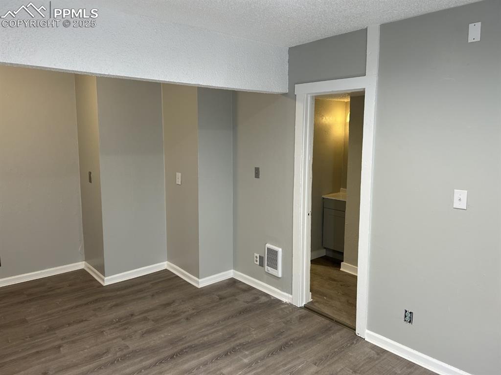 Image 6 of 49: Spare room with dark wood-type flooring and a textured ceiling