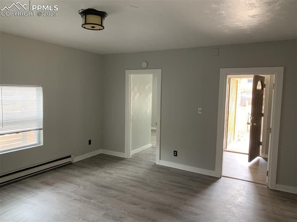 Image 9 of 49: Entrance APT 1 room with wood finished floors and baseboard heating